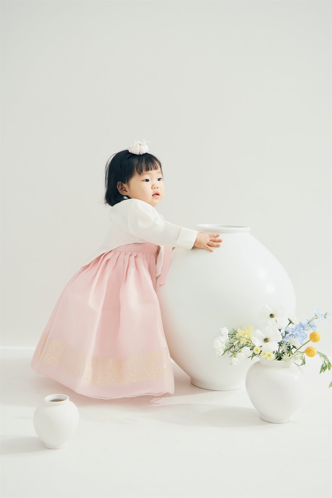 분홍 한복을 입고 흰 달항아리 옆에 서 있는 박주이